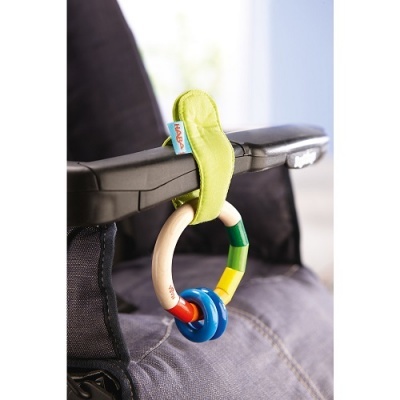 Brinquedo colorido pendurado em carrinho de bebé cinzento com correia verde