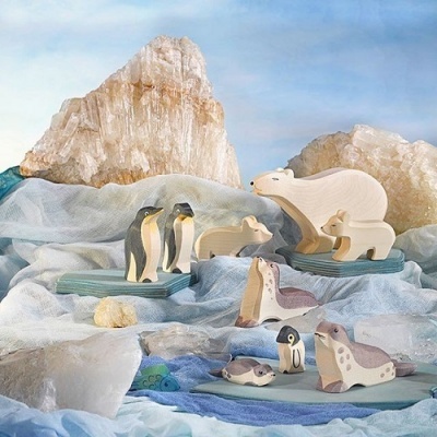 Figuras de animais polares de madeira em cenário simulando gelo e rochas