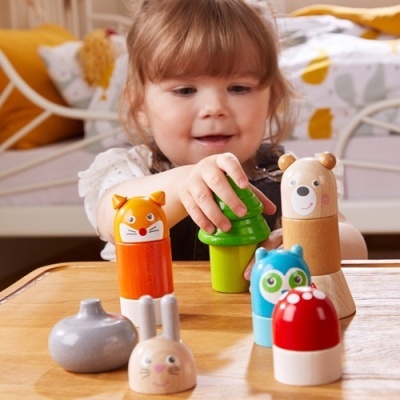 Menina pequena a brincar com brinquedos de madeira coloridos em forma de animais