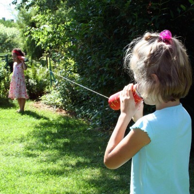 Duas crianças brincando com um brinquedo de copo com fio ao ar livre