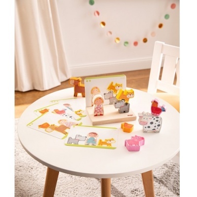 Brinquedos de madeira coloridos em mesa redonda branca num quarto com decoração simples.