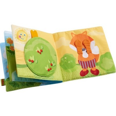 Livro têxtil infantil com ilustrações coloridas de sol, arbustos e raposa.