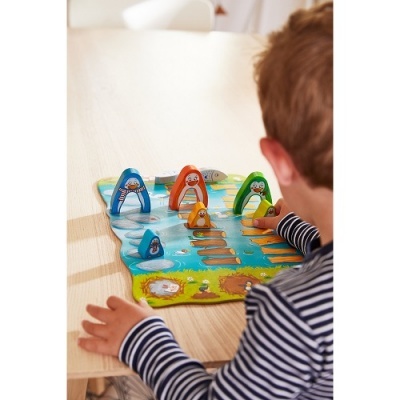 Jogo de tabuleiro infantil com peças coloridas e tema marinho em mesa de madeira clara.