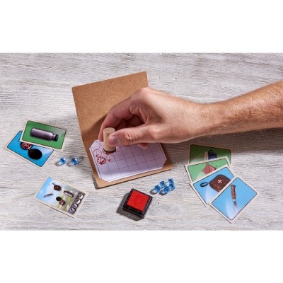 Jogador a marcar bloco com carimbo vermelho e cartas ilustradas em mesa clara