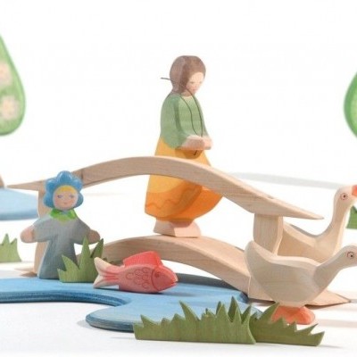 Miniaturas de madeira coloridas com figuras de crianças e patos em ambiente natural estilizado