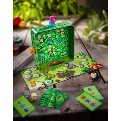 Jogo de tabuleiro com peças coloridas, cartas verdes e caixa metálica decorada com flores.