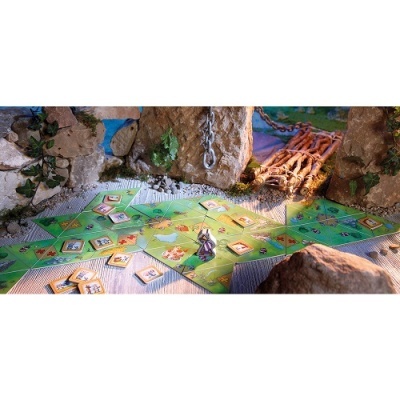 Jogo de tabuleiro com peças coloridas e cenário natural com pedras e ponte de madeira