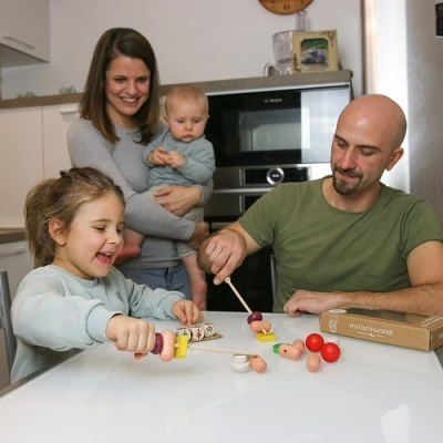 Família brincando com brinquedos de madeira coloridos numa mesa branca em cozinha moderna