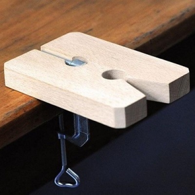 Mola de madeira clara fixa numa mesa de madeira com gancho metálico.