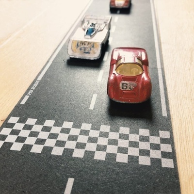 Três carros miniatura em pista de corrida com padrão quadriculado