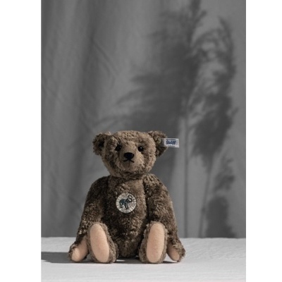 Urso de peluche castanho com patas cor de pele e bordado frontal com cavalo.