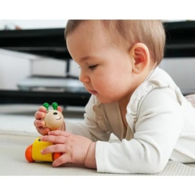 Bebé a brincar com brinquedo de madeira colorido no chão da sala