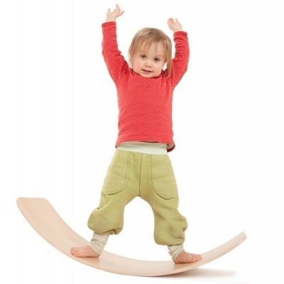 Criança em prancha de equilíbrio de madeira com roupa vermelha e verde