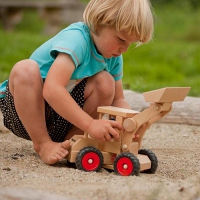 Criança a brincar com carrinho de madeira no chão de areia