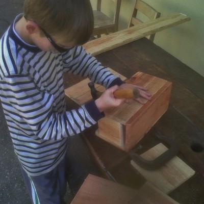 Menino a trabalhar madeira numa bancada