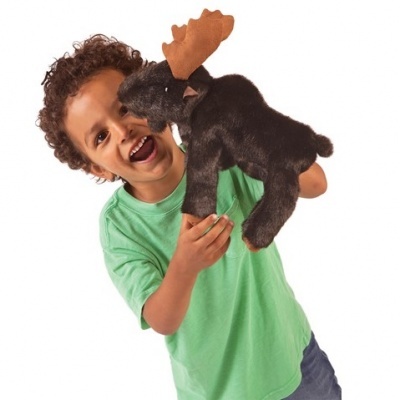 Criança com t-shirt verde segurando fantoche de peluche castanho escuro com galhadas.