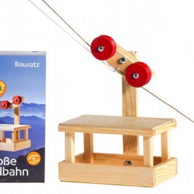 Brinquedo de madeira com plataforma e rolos vermelhos ao lado de embalagem azul com texto em alemão