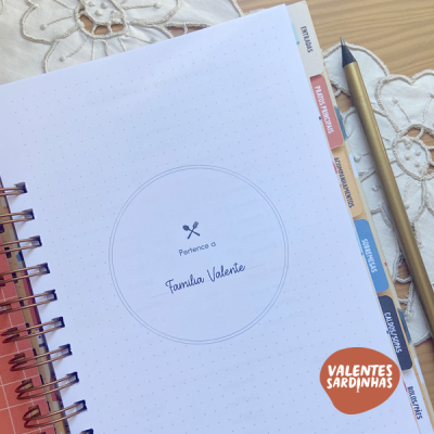 Caderno aberto com divisórias coloridas e caneta dourada ao lado