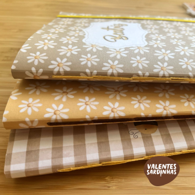 Três cadernos empilhados com capas decoradas e selo Valentes Sardinhas.