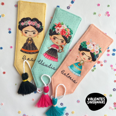 Três marcadores de livros de tecido com ilustrações coloridas e pompons.