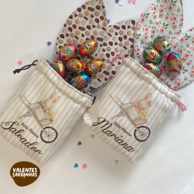 Sacos de algodão às riscas com desenhos de coelho, nomes Salvador e Mariana, cheios de ovos de chocolate coloridos
