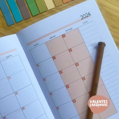 Agenda anual 2024 aberta com dias da semana e caneta castanha com cabeça de urso
