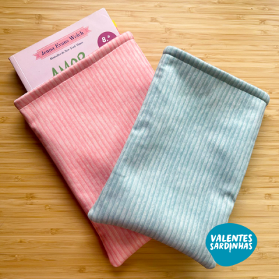 Sacolas de tecido rosa e azul com padrão riscado numa superfície de madeira, uma contendo uma caixa de chocolates Jeanne Etiene Welch