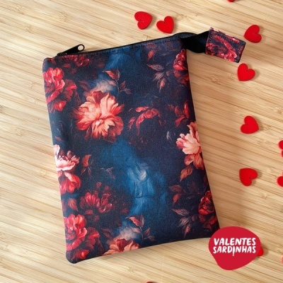 Estojo floral vermelho e azul com fecho preto sobre madeira clara com corações vermelhos
