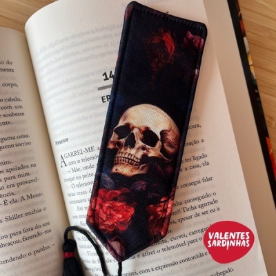 Marcador de livros com caveira e rosas em livro aberto