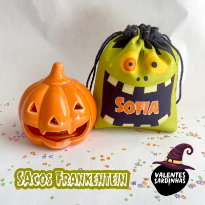 Saco de tecido verde com monstro Frankenstein e abóbora de Halloween ao lado.
