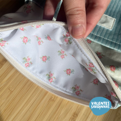 Bolsa azul claro com padrão floral cor-de-rosa e interior forrado com flores cor-de-rosa e fecho branco