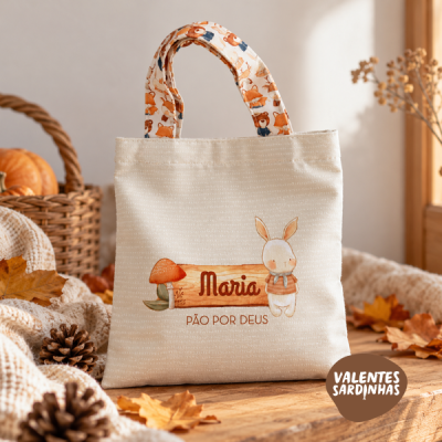 Saco de tecido bege com alças estampadas e ilustração de coelho e cogumelo com texto personalizado.