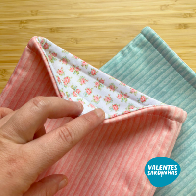 Toalhas coloridas de tecido com padrão riscado e interno floral em fundo de madeira