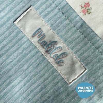 Etiqueta de tecido com a palavra matilde numa peça têxtil de riscas azuis e brancas