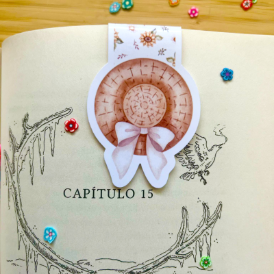 Página de livro com marcador de página em forma de chapéu de palha e pequenos botões coloridos em formato de flor ao redor.