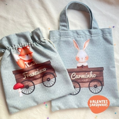Duas bolsas de tecido cinza claro decoradas com desenhos de animais e nomes personalizados