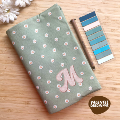 Estojo verde com padrão de margaridas, régua de cores azul, lápis castanho, madeira clara