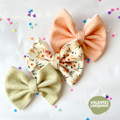 Três laços grandes coloridos com padrões diversos sobre fundo branco com confetes coloridos.