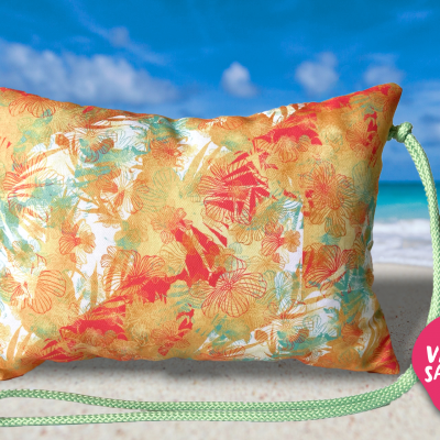 Almofada retangular colorida com cordão verde e etiqueta rosa na praia