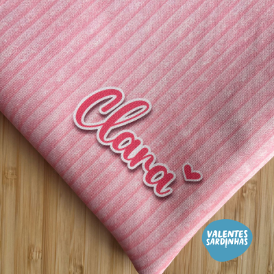 Guardanapo rosa com riscas e nome Clara bordado sobre madeira