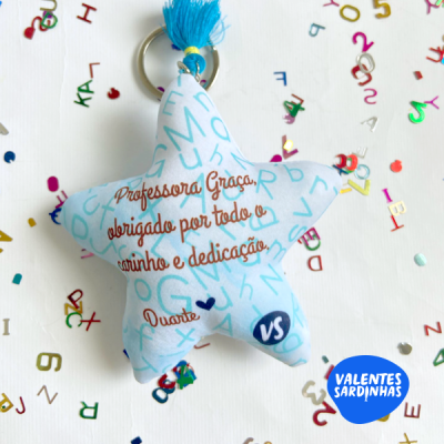 Chaveiro estrela azul claro com texto em castanho e franjas azuis.