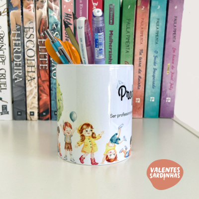 Caneca branca com ilustrações de crianças e balões usada como porta-lápis em mesa com livros ao fundo
