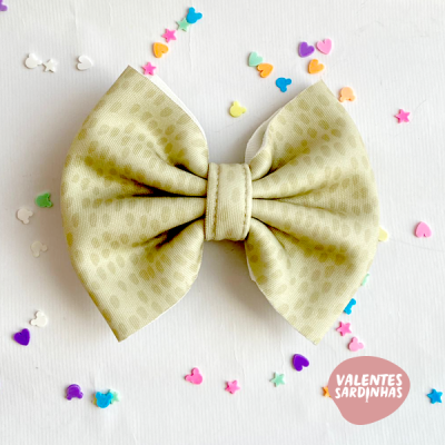 Laço de tecido bege com padrão de bolinhas e confetis coloridos