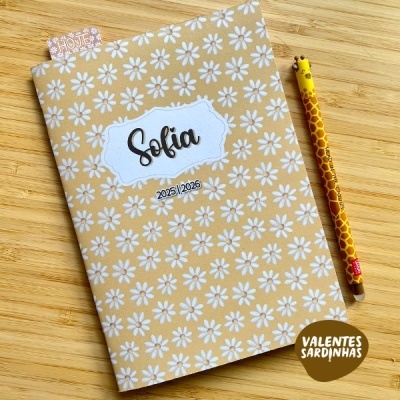 Caderno tecido amarelo com flores brancas e lápis girafa sobre madeira