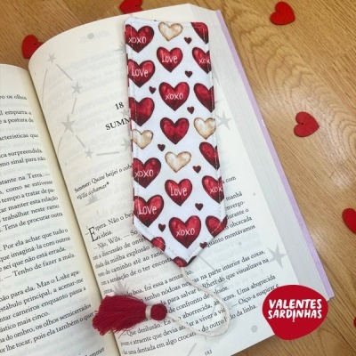 Marcador de livros com corações vermelhos e palavras LOVE e XOXO sobre livro aberto e corações de feltro vermelhos ao redor
