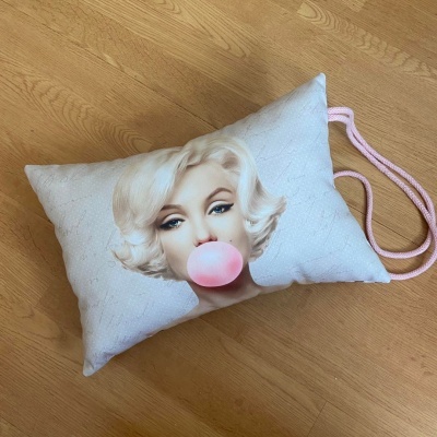 Mala pequena branca com rosto de mulher loira a mascar pastilha rosa