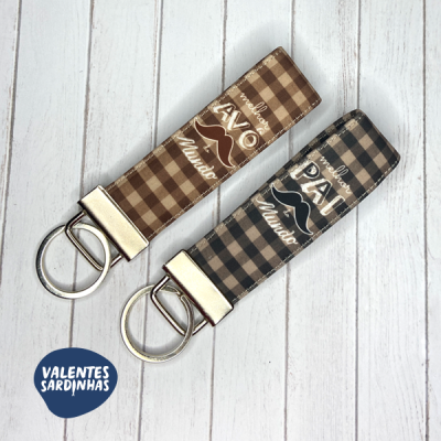 Dois porta-chaves xadrez com inscrições para pai e avô sobre fundo branco de madeira