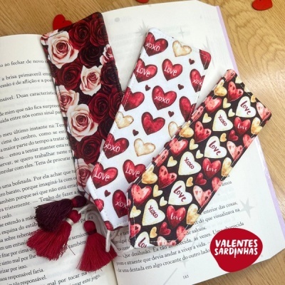 Marcadores de livros de tecido com estampados de corações e rosas sobre livro aberto