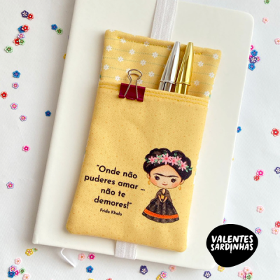 Estojo amarelo de tecido com frase e ilustração de Frida Kahlo, dentro de caderno branco