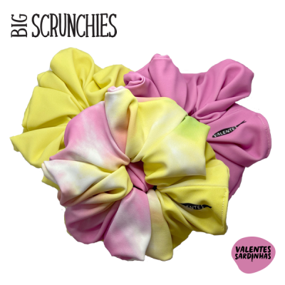 Três big scrunchies em amarelo, rosa e tie-dye com etiquetas VALENTES